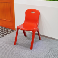 a red plastic chair leaning against a wall